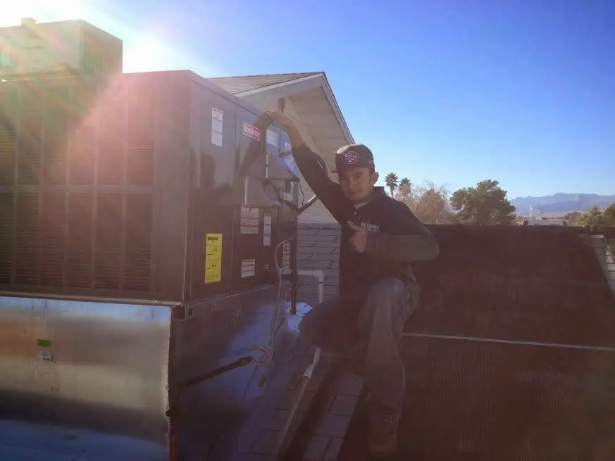 HVAC technician performing Heat Pump Repair on a rooftop unit in Clovis
