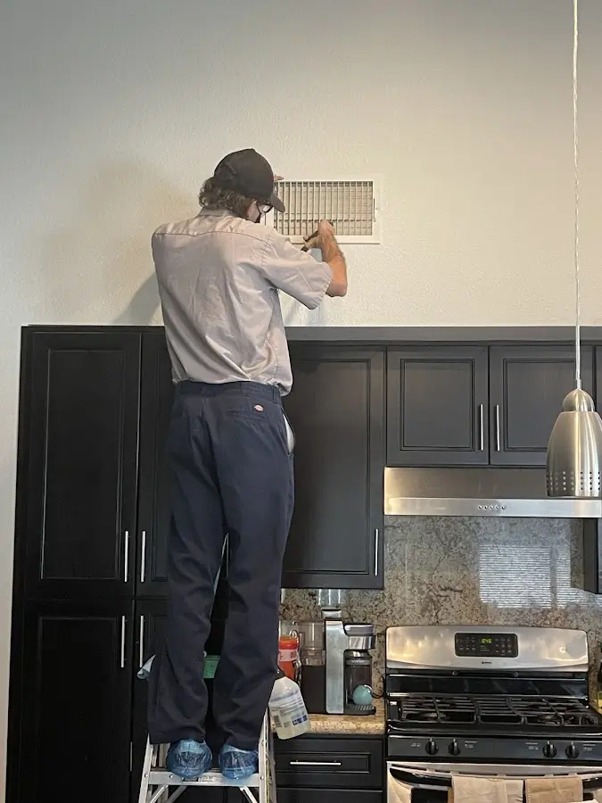 Technician inspecting an air vent during HVAC service in Clovis